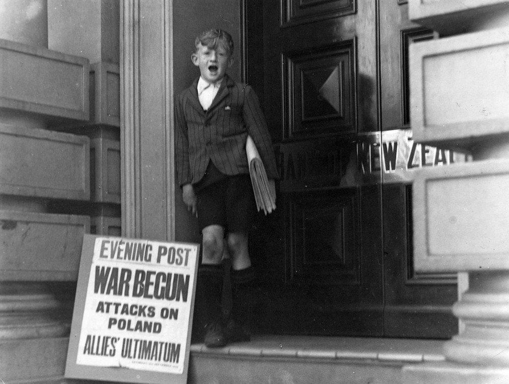 Newspaper boy and an advertising signboard which reads War Begun. Ref: 1/2-066962-F. Alexander Turnbull Library, Wellington, New Zealand.